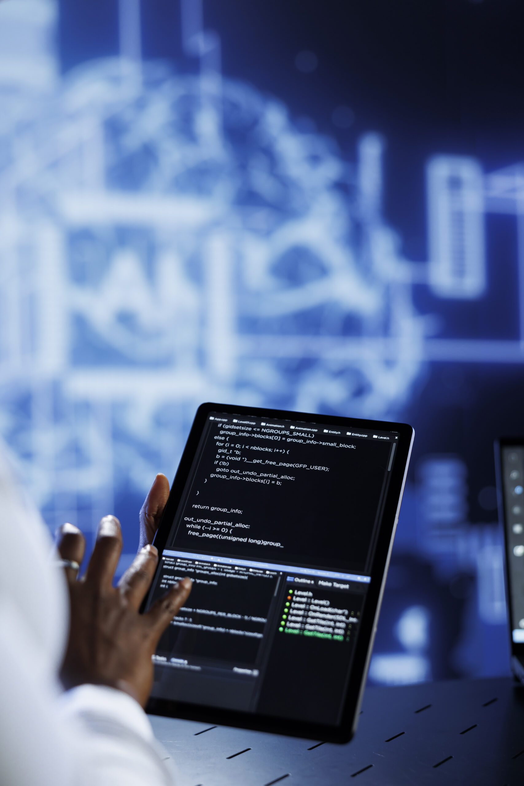 Trained developer updates neural networks made up of interconnected nodes, writing intricate binary code scripts on tablet. Expert uses programming to upgrade AI simulation model, blurry background