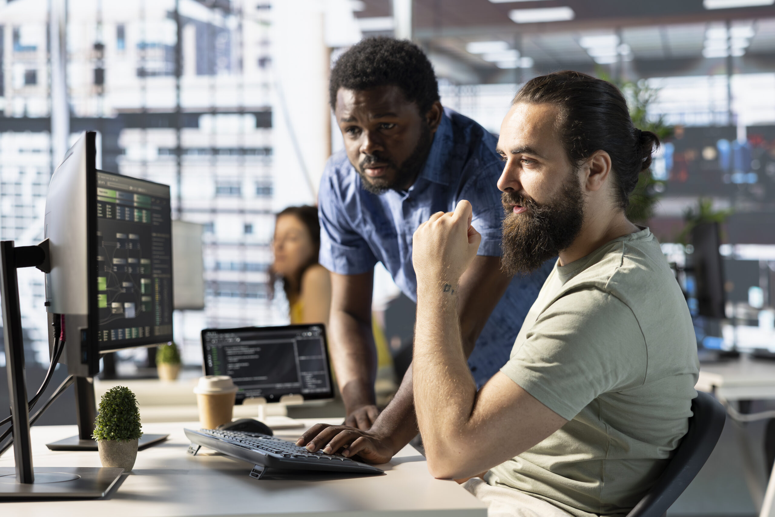 Data engineer and coworker at PC desk developing machine learning algorithms. Programmer and colleague in office solving tasks, training large scale deep learning models using computer